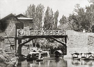 Canal footbridge in Srinagar. Water taxis pass beneath a wooden footbridge on a Srinagar canal.