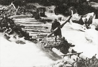 Constructing a timber bridge near Sekwas Pass. Two Kashmiri mountain guides construct a makeshift