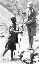 Preparing to cross a Kashmiri stream. George Boon balances precariously on a log as he prepares to