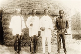 Four Nigerian domestic servants. Portrait of four Nigerian servants standing outside a traditional