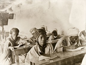 Adult Hausa students in a classroom, Kano. Adult Hausa pupils sit studying at benches in a Nigerian