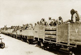 African schutztruppes travel by rail. African schutztruppes travel in crowded, open railway wagons