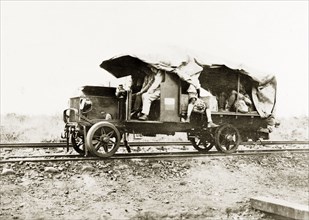 A truck converted to run on rails. Several European men travel in the cab and coach of a truck