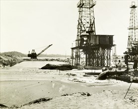 Raising the land at the Chauk-Lanywa oilfield. Construction workers use a dredger to pump sand onto