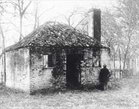 Former slave accommodation. A man stands outside a dilapidated building that was once used to