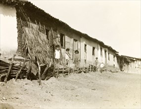 A row of houses in Natal, Brazil. Brazilian children stand outside a row of single-storey houses