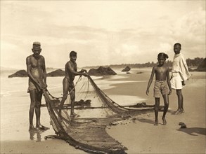 Fishermen on Azhikkal beach. Fishermen prepare their nets on a wide sandy beach. Azhikkal, Kerala,