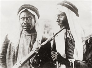 Armed Arab dissidents. Portrait of two men dressed in typical Arab attire and armed with rifles. An