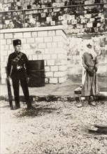 Arab prisoner of the Great Uprising. A young Arab prisoner stands handcuffed in a courtyard, under