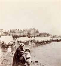 Bathing machines on Eastbourne beach. Minnie Murray rolls up her daughter's sleeves on the beach at