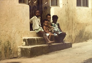 Children in Mombasa. Four children sit on stone steps outside a doorway in Mombasa. Mombasa, Kenya,