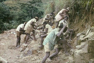 Road building at Mafuga Forest. A group of labourers drill rocks with hand chisels in Ishasha
