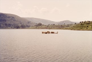 Dugout canoes on Lake Bunyonyi. Two dugout canoes filled with bamboo baskets float on the calm