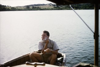 Shaving on Lake Victoria. District Forest Officer Bob Plumptre sits shaving in the stern of a