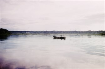 Fishing off Buvuma Island. Two early-morning fishermen man a small boat off Buvuma Island, on the