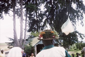 A Christmas hat. Seen from behind, an African man wears a trilby hat decorated with flowers and