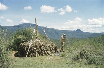 Henry Osmaston surveys Pcholio Peak. Henry Osmaston (Working Plans Officer of the Uganda Forest