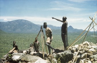 Surveying in the Karasuk hills. Accompanied by Suk (Pokot) porters, a Ugandan Forest Guard stands