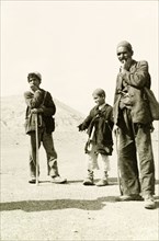 Portrait of an Afghan man and two boys. Dressed in tattered clothes, an Afghan man and two boys