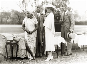 Standing in comfort on the lawn. Sir Maurice and Lady Hallett with guests at their garden party.