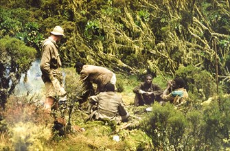 Breakfast in the Rwenzori Mountains. African porters with a British forestry survey team sit around