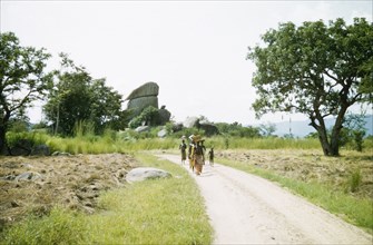 A rural road in West Nile. A small group of women and children walk along the main road to Arua.