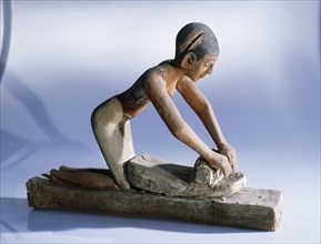 Wooden model of a woman grinding grain