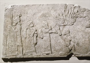 Stone relief depicting Babylonian and Chaldean prisoners in camp, under guard, with a log fire burning behind