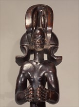 Wood figure wearing headdress that is characteristic of Chokwe chiefs and also found on important masks