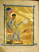 An illumination from a manuscript depicting St Luke at his desk on which there appears to be a set of engravers tools