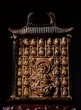 Miniature gilt bronze reliquary in the form of a building, dating from the late Tang dynasty, ornamented with miniature Buddhas in relief around the central image of the Bodhisattva Guanyin seated on ...
