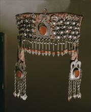 A silver headdress with a fringe of pendant oragne stones