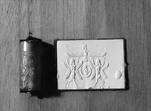 Cylinder seal and impression depicting two four winged sphinxes support the winged disk of Ahuramazda
