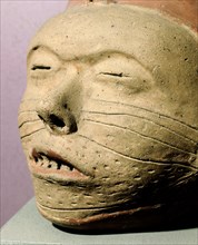 Pottery effigy head vessel with sealed eyelids, stitched mouth and facial decorations