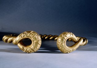 Torque made from twisted gold with solid ends decorated in relief