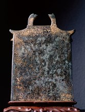 The back of a miniature gilt bronze reliquary in the form of a building, dating from the late Tang dynasty, ornamented with miniature Buddhas in relief around the central image of the Bodhisattva Guan...