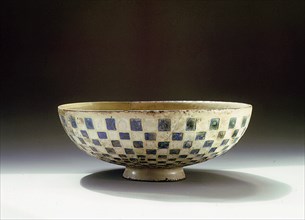 A pottery bowl with a blue and white chequer pattern on the outside