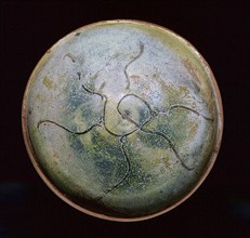 A redware pottery bowl with an abstract design scratched through the white slip before glazing