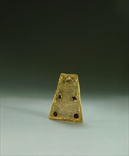 A gold & garnet fragment which would have been fastened with others to a necklace of cloth or leather