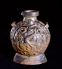 A molded brown glazed flask decorated on one side with a phoenix