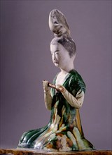 Figure of a kneeling female musician with a distinctive high chignon hairstyle, holding a flute
