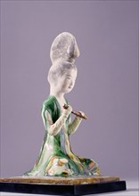 Figure of a kneeling female musician with a distinctive high chignon hair style, holding a flute