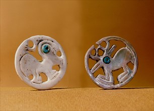Pendants, one with a bird design, one with a deer
