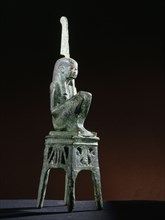 Seated bronze figure of the goddess Maat, wearing a tripartite wig, seated on an openwork throne of winged uraei and Hathor heads