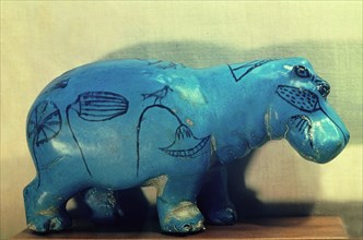 A statue of a hippopotamus decorated with water plants and papyrus plants
