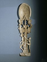 Unguent spoon in the form of a  palm tree with  a guard at  its  foot