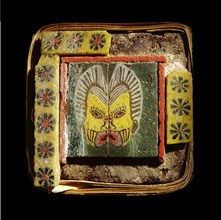 Furniture inlay of glass tiles, depicting a theatrical mask of an old man, framed by flowers