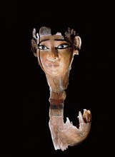 Fragment of a wooden statue destroyed by termites, leaving a finely carved face with heavy eye make up