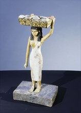 A model of a servant girl carrying on her head a basket of loaves and pieces of meat
