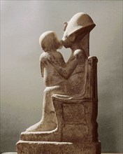 Akhenaten kisses his daughter as she sits on his lap